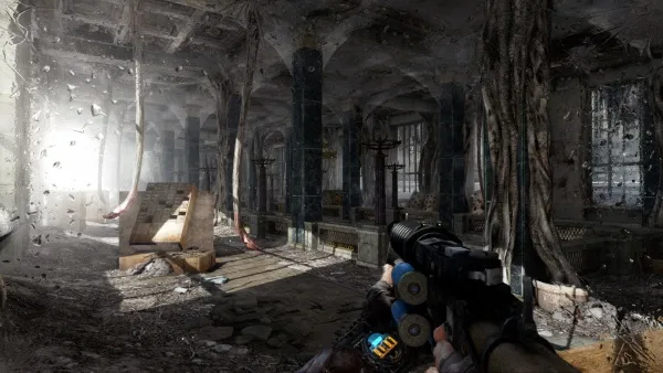 A first-person perspective of a player holding a gun in a post-apocalyptic setting, with overgrown trees and debris inside an abandoned building. The scene is dimly lit by sunlight filtering through broken windows, creating a contrast between light and shadow. The atmosphere is tense and eerie, with the player seemingly preparing for combat or exploration.