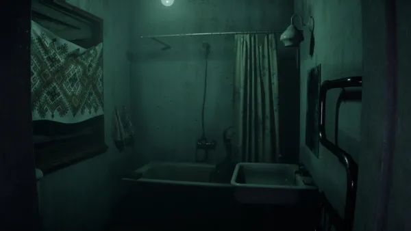 A dimly lit bathroom with a greenish tint, featuring a bathtub with a shower curtain, a sink, and a towel hanging on the wall. The room has a vintage feel with a patterned cloth draped over the bathtub's edge and a single light bulb providing illumination.