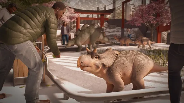 In a snowy, prehistoric-themed park, a man in a green puffer jacket and gray jeans is feeding a baby Triceratops. The scene includes other dinosaurs like Stegosaurus and T-Rex, with visitors observing from behind barriers. Cherry blossom trees add a touch of color to the wintry landscape.