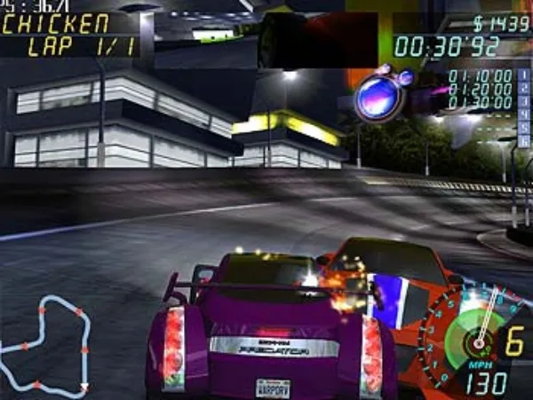 A high-speed car racing game scene with a purple sports car on the track, an orange car chasing behind. The game interface displays lap information, speedometer, and other data. Nighttime urban environment with buildings and streetlights in the background.
